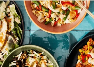 A top-down view of different bowls of food on a tile countertop.