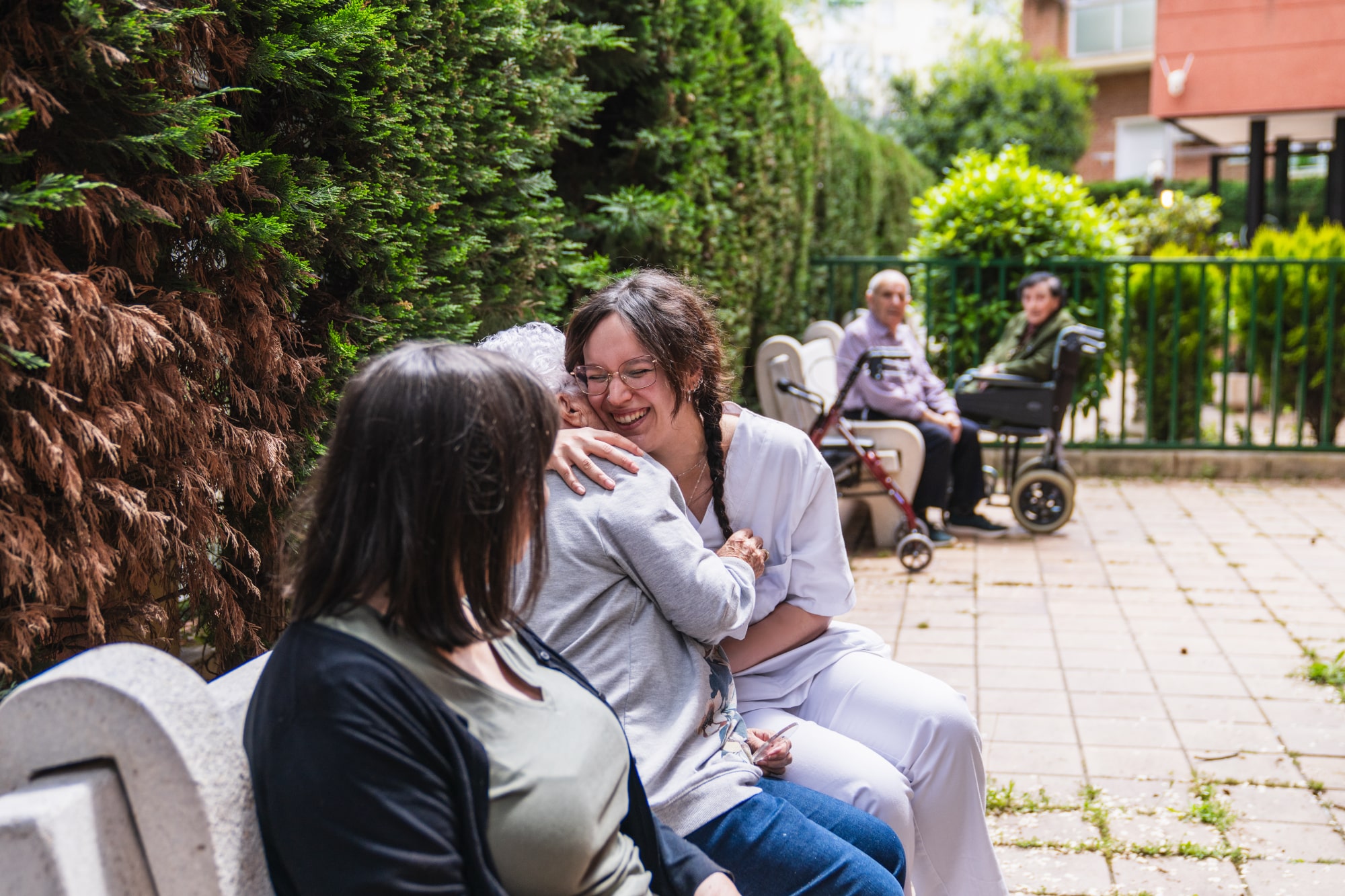 An adult foster care worker sitting with a client in a public park.